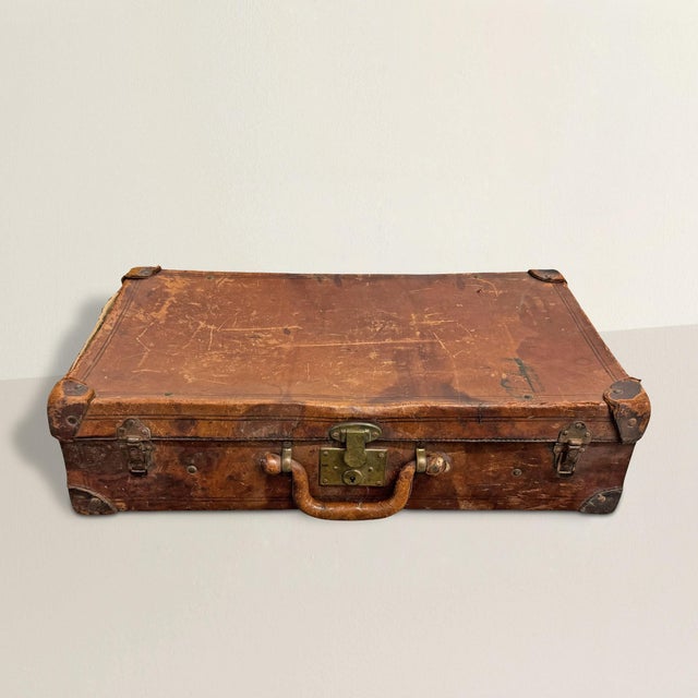 This 19th-century English leather suitcase is a charming relic of refined travel in a bygone era. Crafted from supple...