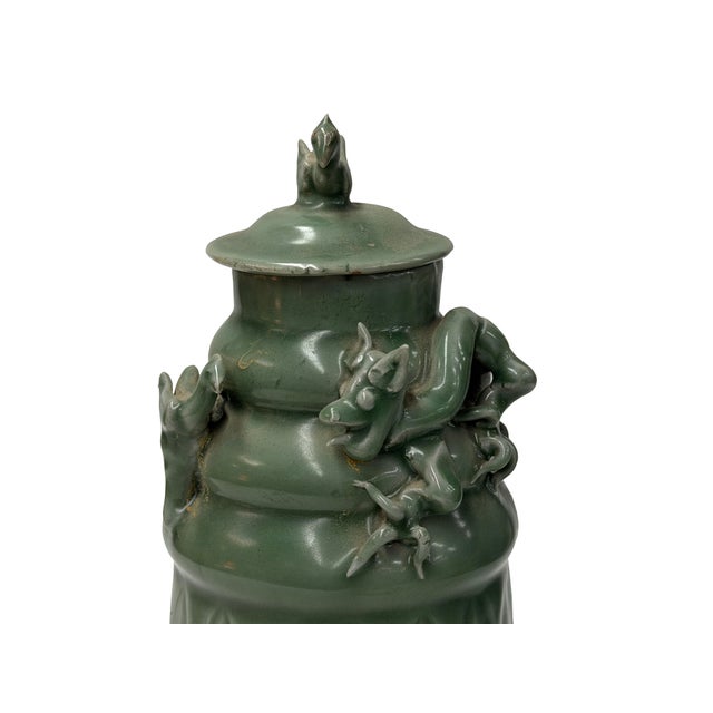 This hand-crafted celadon-glazed ceramic jar, featuring a harmonious blend of smooth, semiglossy finishes and intricate,...