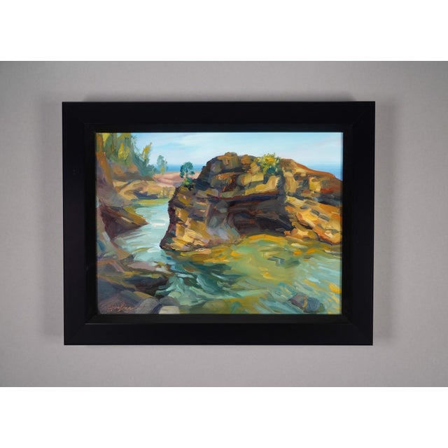 This oil painting captures a serene coastal scene, featuring rugged rocks jutting into a tranquil body of water. The...
