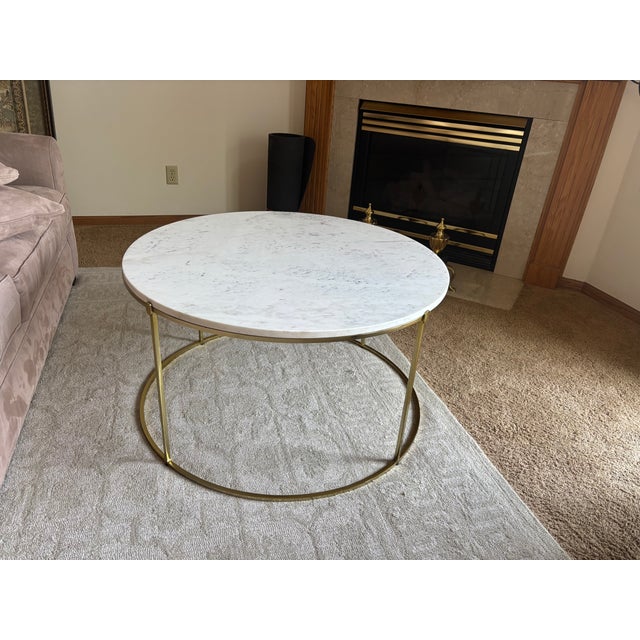 White round marble coffee table with iron legs in a brass finish. Purchased from Anthropologie around 2017 (although there...