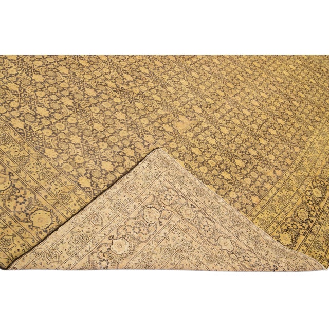 Beautiful antique Persian Tabriz hand-knotted wool rug with a tan field. This piece has a designed frame and brown accents...