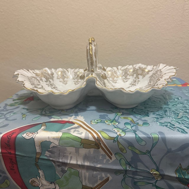Rococo-style divided tray featuring two deep, shell-shaped compartments. Adorned with intricate gold gilt floral patterns,...