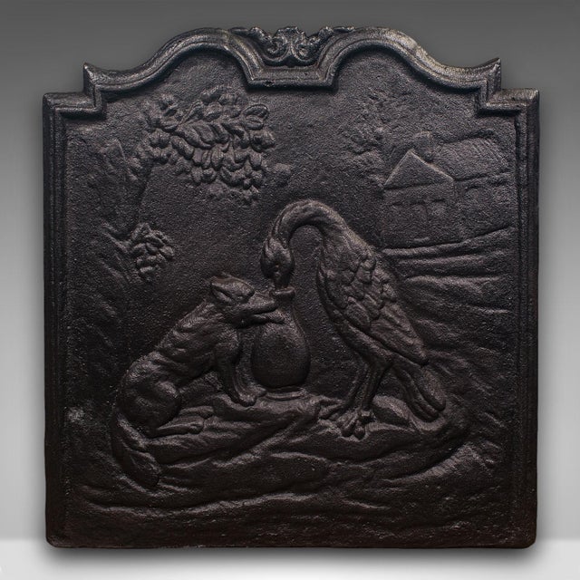 This is an antique decorative fire back. An English, cast iron relief fireplace reflector with Fox and Stork motif after...