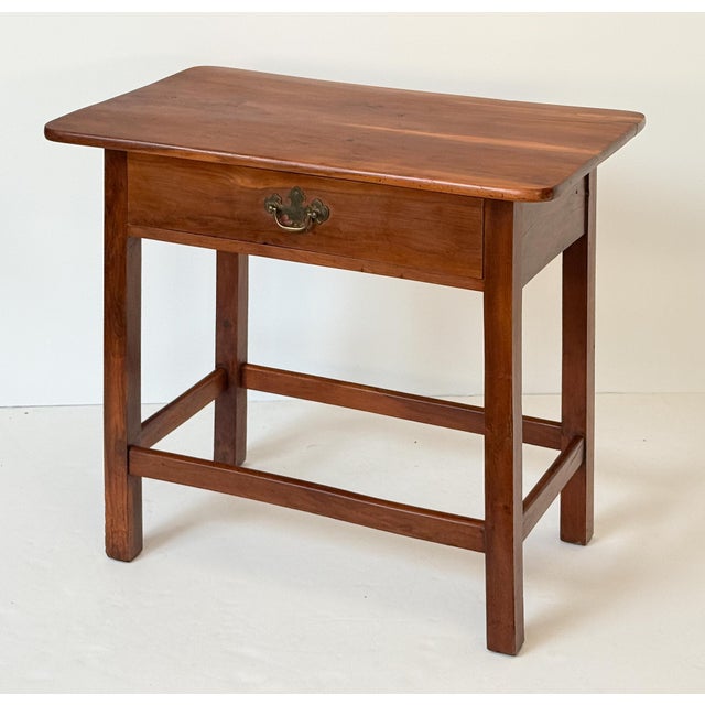 A fine French end or serving side table of patinated cherry wood, featuring a rectangular plank top with lightly rounded...
