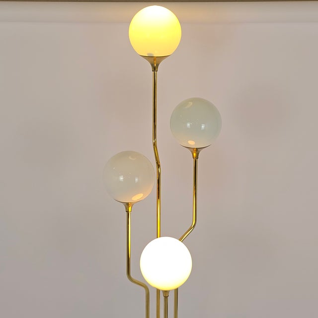 Iconic MCM brass lamp with 4 angled, tiered stems topped by white-glass globes. Italian designer Goffredo Reggiani for...