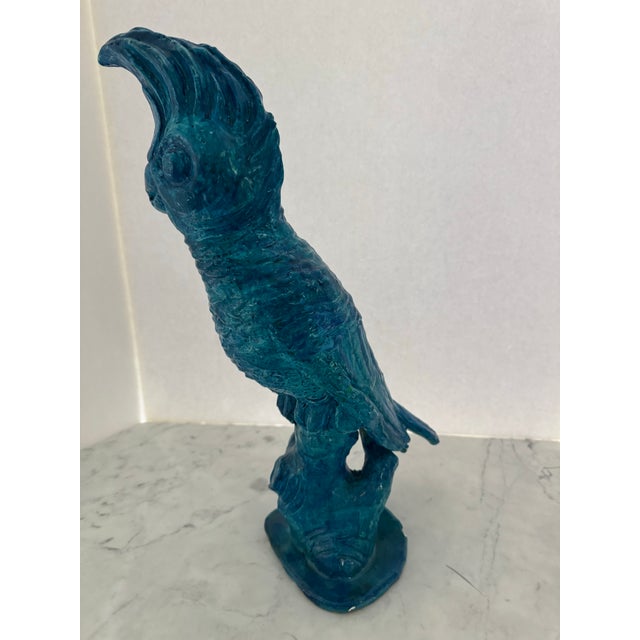 A hand thrown sculpture of a cockatoo glazed in a vibrant shade of turquoise.