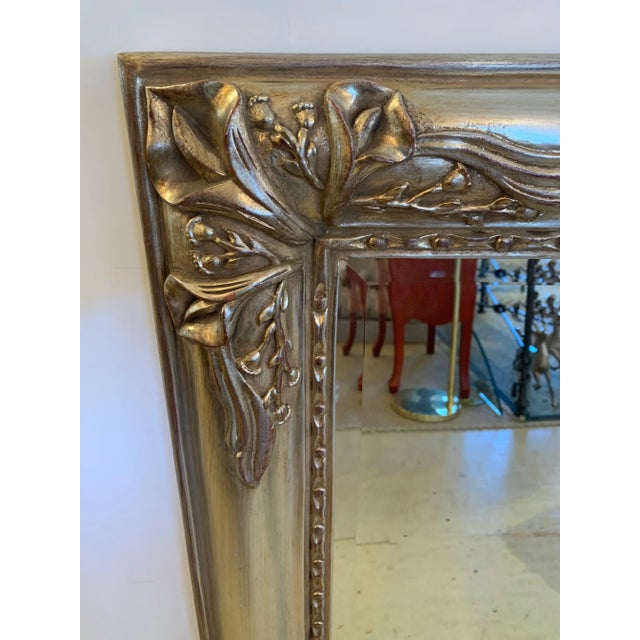 Beautiful bevelled rectangular mirror having silver giltwood carved frame adorned with calla lilies.