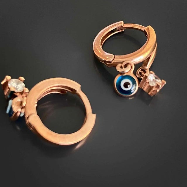 The Baby Evil Eye Earrings are the perfect combination of style and protection. These dainty rose gold plated earrings...