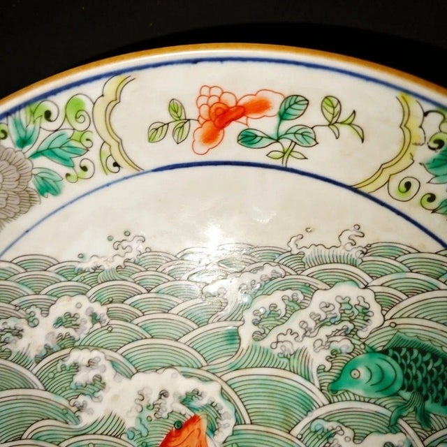 Gorgeous Chinese wucai porcelain display plate hand-painted with multiple colorful carp swimming amid rolling green ocean...