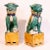 A very handsome pair of foo dogs, seated on ochre glazed plinths, one with a ball under its paw, the other with a puppy....