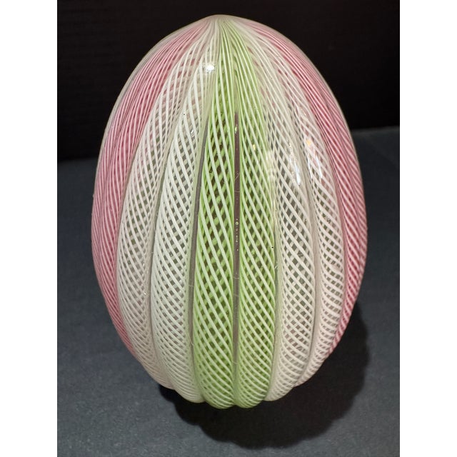 Venetian art glass egg in the zanfirico latticino technique, featuring twisted cane work in pink, green, and white on a...