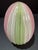 Venetian art glass egg in the zanfirico latticino technique, featuring twisted cane work in pink, green, and white on a...