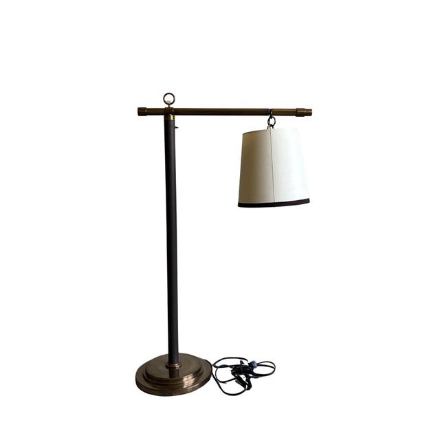 Elegant adjustable floor lamp attributed to Baker Furniture, showcasing a sophisticated blend of antiqued brass, black...