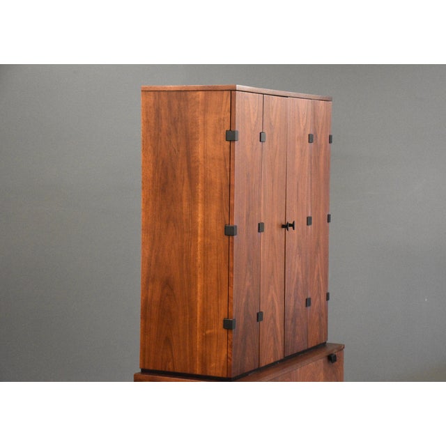 A mid century modern walnut tall chest on chest dresser armoire with black accents designed by Milo Baughman for...