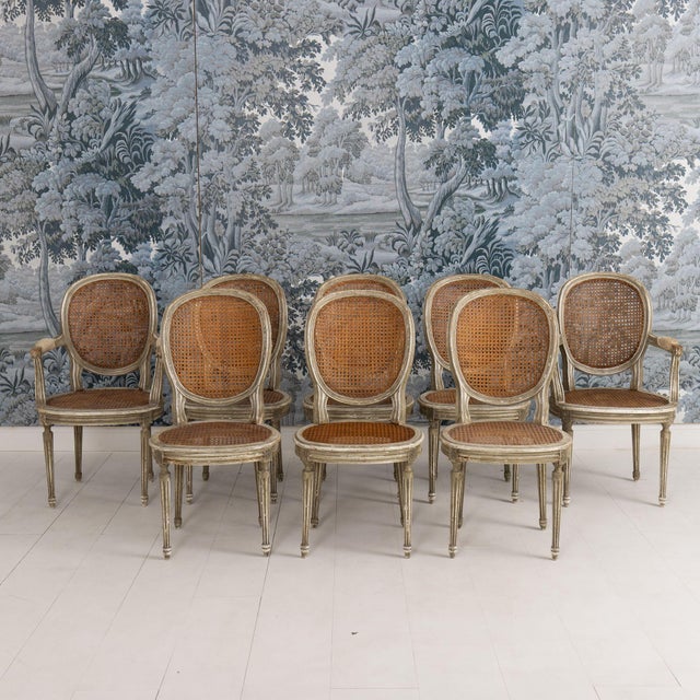 A charming set of eight 19th c. French Louis XVI hand-woven cane chairs with oval backs and wearing original paint. The...