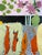 Four orange fish stand upright against a pale green and gray ground beneath a bold black band, with mauve flowers and soft...