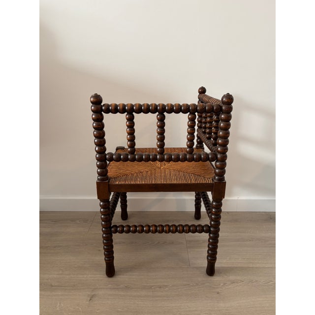 Antique corner chair in dark-stained wood, remarkable for its legs and back adorned with numerous turned, bead-like...