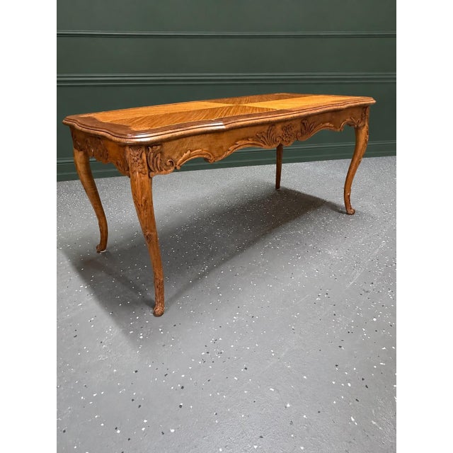 This is an elegant Louis XV style coffee table featuring a beautifully detailed marquetry and parquetry top framed by...