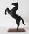 Vintage folk art metal rearing horse figure on wood base. Some age wear to painted black finish. Made in India.