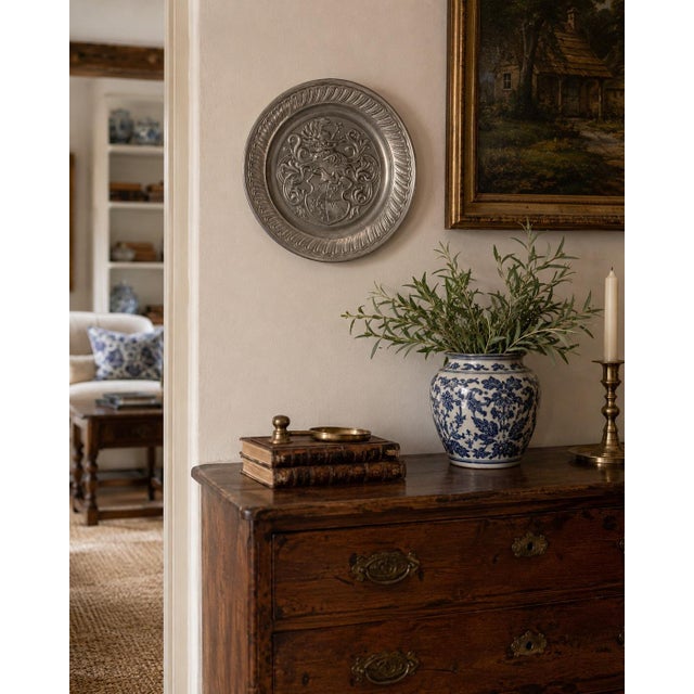 A handsome mid-20th-century German pewter wall plate centered by an elaborate heraldic coat of arms. The relief decoration...