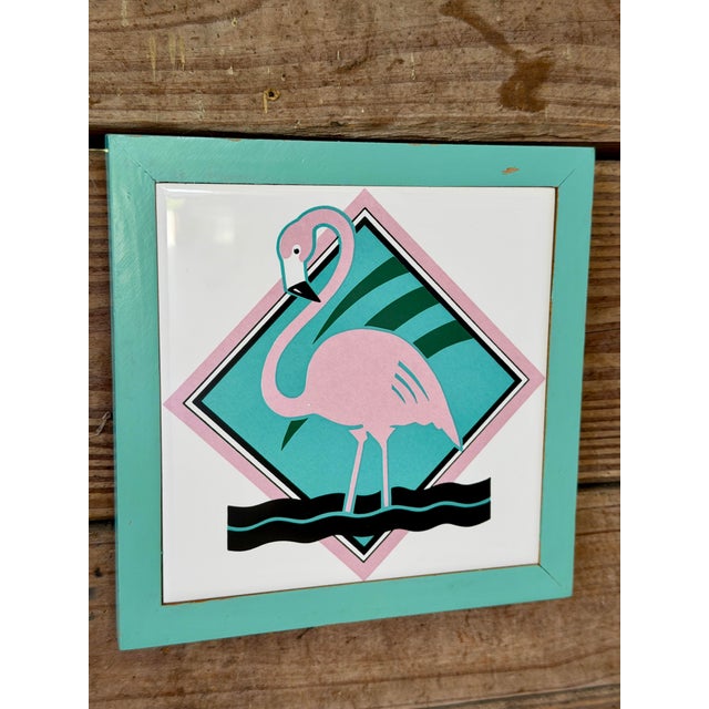 A fun and unmistakably 1980s wall accent featuring a graphic pink flamingo set against a geometric pastel background....
