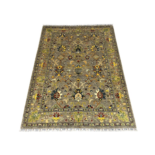 A gray field sets off scrolling vines, stylized flowers, and a small central motif in gold, cream, blue, and burgundy....