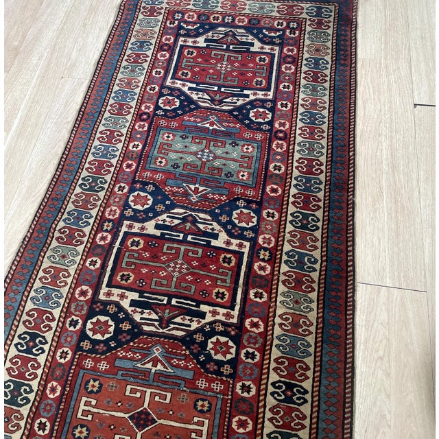 This magnificent Caucasian Kazak runner, dating back to the 1880s, is a true collector's item. Hailing from the rugged...