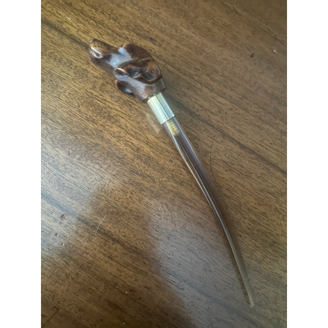 A finely crafted antique letter opener, featuring a hand-carved wooden dog head handle with expressive detailing and...