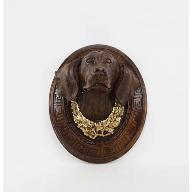 Mid-20th century wooden hand-carved decorative dog head. (The foliage below the dog's head is decorated with gold leaf.)...