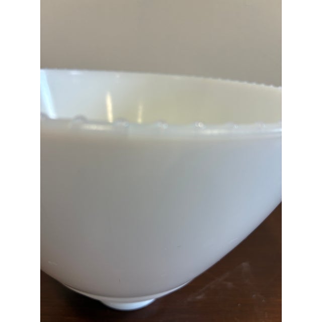 A classic vintage milk glass lamp shade featuring a softly tapered cone silhouette and subtle ribbed detailing near the...