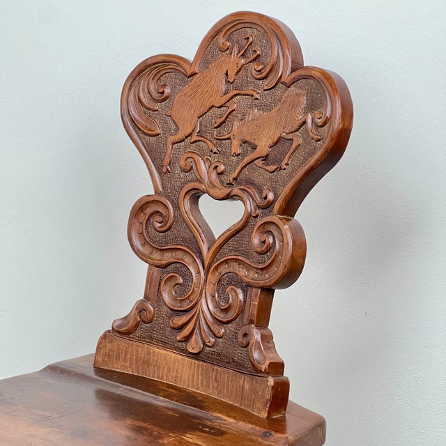 A Delightful Swiss Alpine Folk Art Escabelle Chair. This charming antique features a beautifully carved backrest adorned...