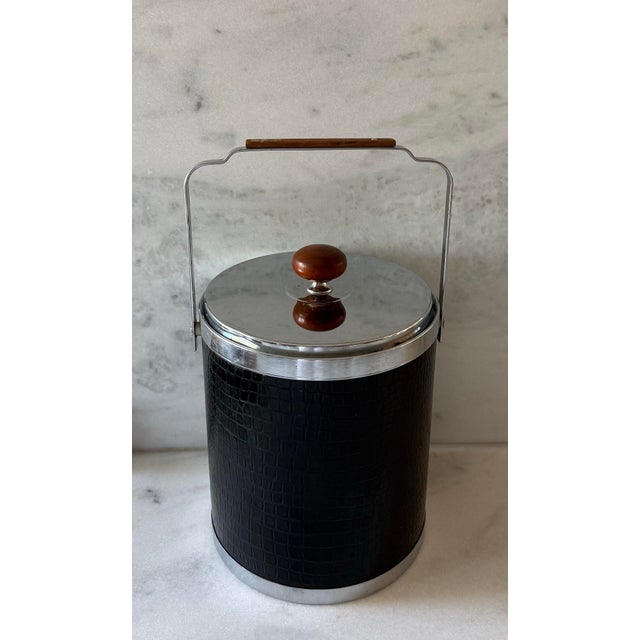 1960s mid century ice bucket by Kromex, featuring black faux alligator embossed vinyle, chrome lid and base and a warm...