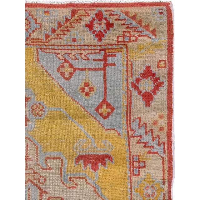 A wool pile of symmetric knots on a cotton foundation. The soft yellow semi-open field presents a beige medallion, pale...