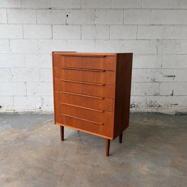 A tall Danish teak chest from the 1960s, with a narrow vertical profile and six graduated drawers that make it especially...