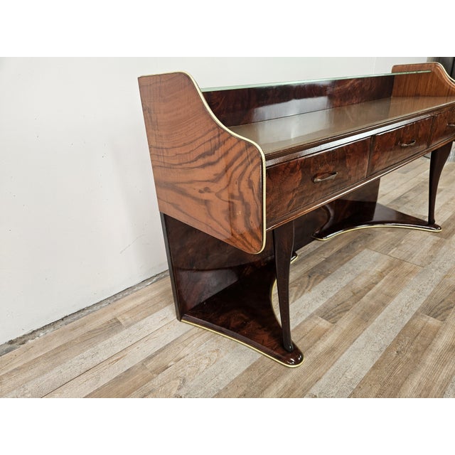 A 1950s-style dressing table or entryway cabinet with an elegant and refined design, clad in burl wood that enhances the...