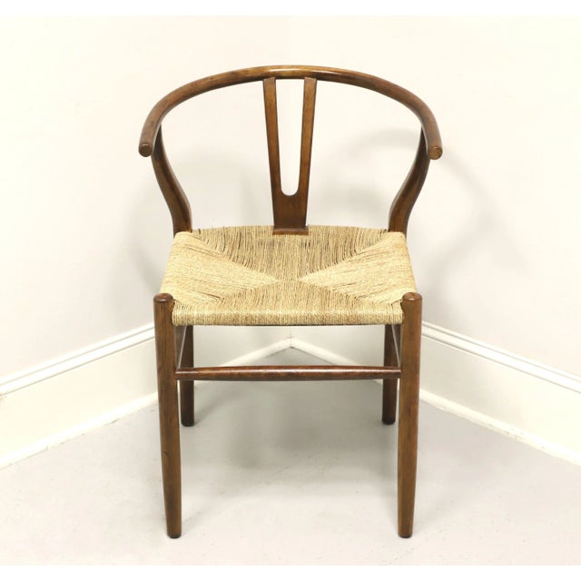 A Chinese Ming style armchair, unbranded. Solid oak with a chestnut color finish, slender curved arms that form the crest...