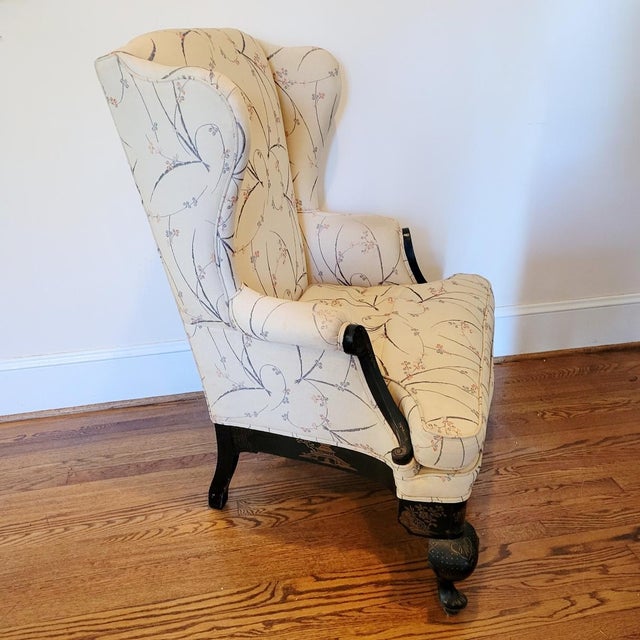 A large circa 1900 English Queen Anne Revival wingback chair featuring a black japanned wood frame decorated with gilt...