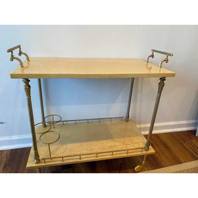 This mid-century modern bar cart of polished brass and lacquered goatskin, circa 1965, was made in Italy by Aldo Tura for...