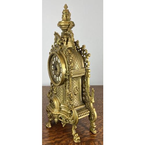 This Vintage French clock is an elegant and highly decorative piece, showcasing an ornate sculptural form with elaborate...