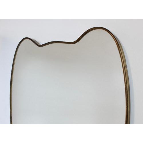 Mid-century italian wall mirror with brass frame (circa 1960s). The mirror is classically-shaped and distinctive in a...