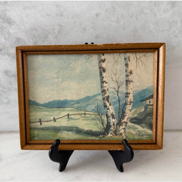 Small vintage watercolor painting of a rural landscape featuring a birch tree in the foreground and a fence and house in...