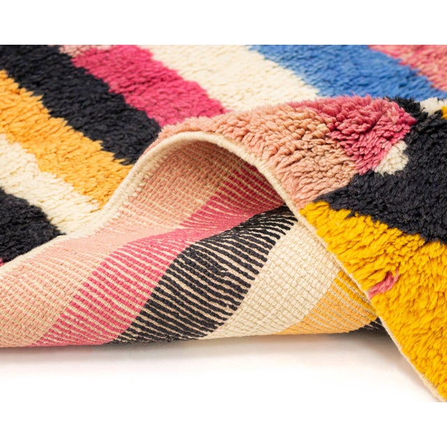 Vibrantly colored Hand-knotted wool rug featuring a spectrum of stripes in shades of Pink, Blue, Mustard Yellow, and deep...