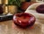 A striking large-scale handblown art glass ashtray or catchall bowl in a rich ruby red hue, featuring an elegant...