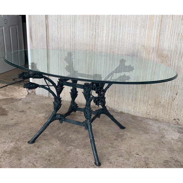 Dramatic Italian centre table with oval glass top supported by an iron base with scroll legs embellished with flowers....
