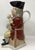 This drinking mug is modelled as a "Squire" with a tricon hat, seated with stragley hair on a corner chair, holding bear...