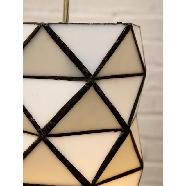 A striking pair of vintage hanging pendant lights featuring faceted geometric shades composed of milky white glass panels...