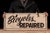 Double-sided painted wood advertising sign reading "Bicycles Repaired" in bold black lettering against a cream ground. The...