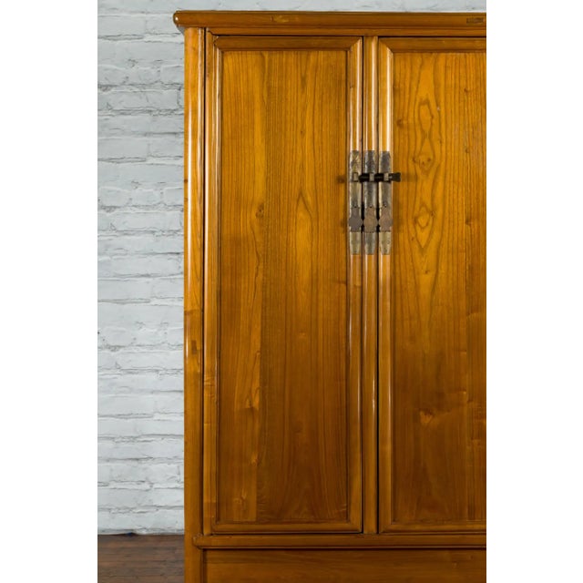 A Chinese Qing Dynasty period elm wood noodle cabinet from the 19th century, with brass hardware, tapering lines and...