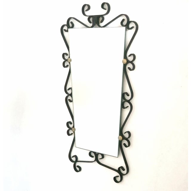 Forged hell-shaped mirror decorated with scrolls and gilt brass discs with its original green felt backing 20th century...