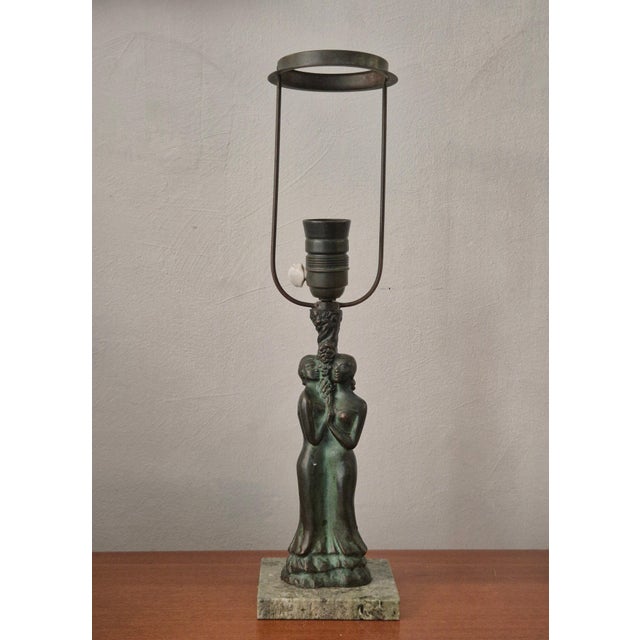 Scandinavian Grace table lamp in bronze with green marble base, decor of two female figures embracing a tree. Shade is not...